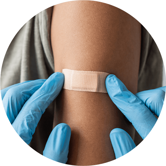 Blue gloves placing bandaid on arm after vaccination